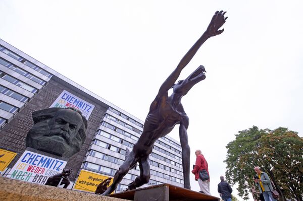 People walk between sculptures by artist Rainer Opolka in front of the Karl Marx Monument in Chemnitz People walk between sculptures by artist Rainer Opolka in front of the Karl Marx Monument in Chemnitz - Sputnik International