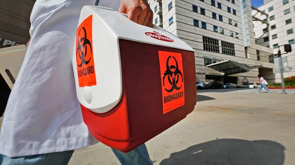 A research assistant with the David Geffen School of Medicine at UCLA carries a portable cooler marked with a biohazard label past the Ronald Reagan UCLA Medical Center in Los Angeles, Thursday, Feb. 19, 2015 - Sputnik International