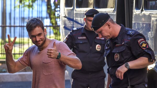 In this file photo taken on July 31, 2018 Member of the Pussy Riot punk group Pyotr Verzilov (L) gestures as he walks with police during a court hearing at a courthouse in Moscow, as members of the Russian protest-art group are accused of disturbing public order after invading the pitch during the World Cup final in Moscow. - Sputnik International