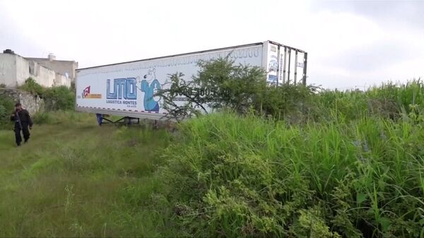 A police officer walks past an abandoned trailer full of bodies in Tlajomulco de Zuniga, Jalisco, Mexico September 15, 2018 in this still image taken from a video obtained September 17, 2018.  - Sputnik International