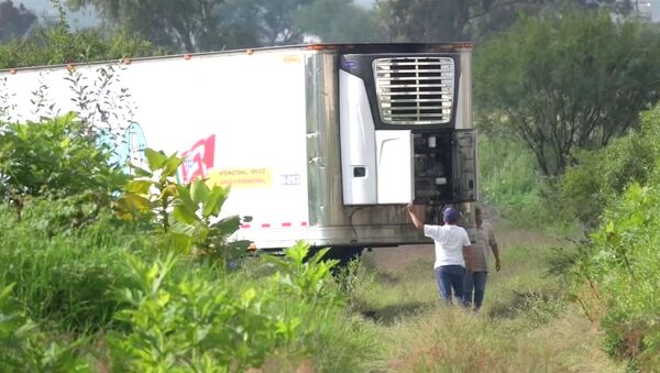 Men stand by an abandoned trailer full of bodies that has been parked in Tlajomulco de Zuniga, Jalisco, Mexico September 15, 2018 in this still image taken from a video obtained September 17, 2018. - Sputnik International