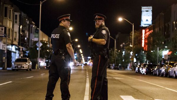 Toronto Police officers stand watch at the foot of Danforth St. at the scene of a shooting in Toronto, Ontario, Canada on July 23, 2018. A gunman opened fire in central Toronto on Sunday night, injuring 13 people including a child. Two dead incluiding gunman, police reported. - Sputnik International
