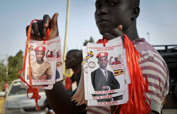A supporter holds up images of Bobi Wine, a popular Ugandan singer who is now a rising opposition politician A supporter holds up images of Bobi Wine, a popular Ugandan singer who is now a rising opposition politician - Sputnik International