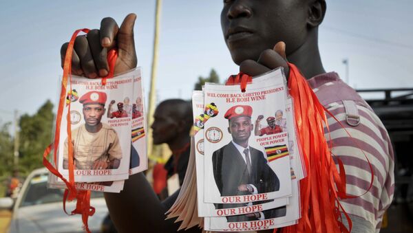 A supporter holds up images of Bobi Wine, a popular Ugandan singer who is now a rising opposition politician - Sputnik International