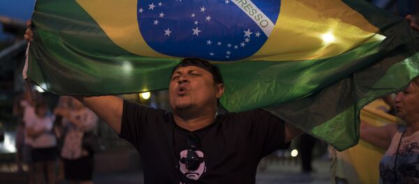A man sings the Brazil's national anthem as he waves the national flag in support leading presidential candidate Jair Bolsonaro, outside Bolsonaro's residence in Rio de Janeiro, Brazil - Sputnik International