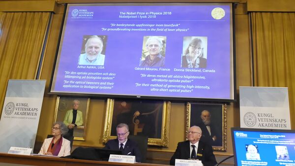 Members of the Nobel Committee for Physics (L-R) Olga Botner, Goran K Hansson and Mats Larsson sit in front of a screen displaying portraits of Arthur Ashkin of the United States, Gerard Mourou of France and Donna Strickland of Canada during the announcement of the winners of the 2018 Nobel Prize in Physics. - Sputnik International