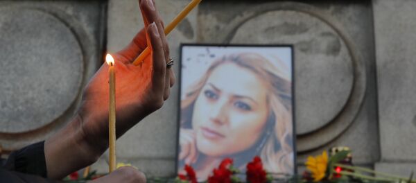 A woman holds a candle next to a portrait of slain television reporter Viktoria Marinova during a vigil at the Liberty Monument in Ruse, Bulgaria, Monday, Oct. 8, 2018. - Sputnik International