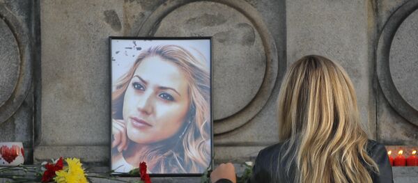 A woman places flowers next to a portrait of slain television reporter Viktoria Marinova during a vigil at the Liberty Monument in Ruse, Bulgaria, Monday, Oct. 8, 2018 - Sputnik International