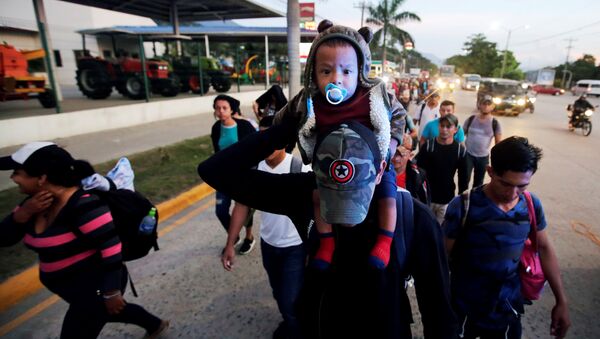 A man carries a child along other Hondurans fleeing poverty and violence, as they move in a caravan toward the United States, in San Pedro Sula, Honduras October 13, 2018 - Sputnik International