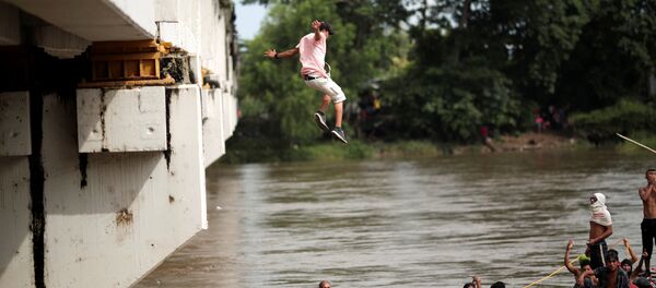 A Honduran migrant jumps from the bridge that connects Mexico and Guatemala to avoid the border checkpoint in Ciudad Hidalgo A Honduran migrant jumps from the bridge that connects Mexico and Guatemala to avoid the border checkpoint in Ciudad Hidalgo - Sputnik International
