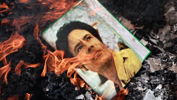 A portrait of Muammar Gaddafi burning in a fire. - Sputnik International