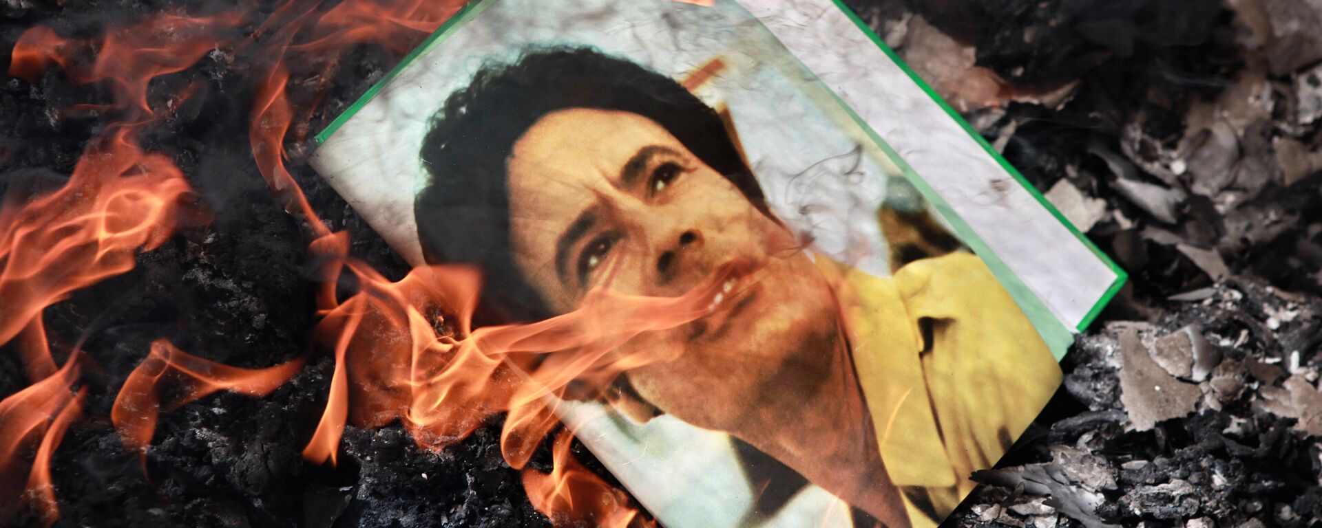 A portrait of Muammar Gaddafi burning in a fire. - Sputnik International, 1920, 15.05.2025