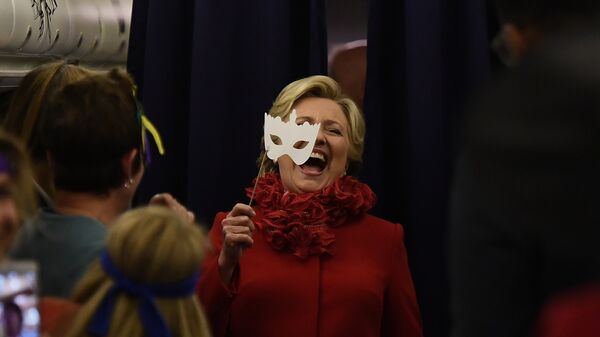 US Democratic presidential nominee Hillary Clinton smiles holding a mask onboard her campaign plane Erlanger, Kentucky, on October 31, 2016 - Sputnik International