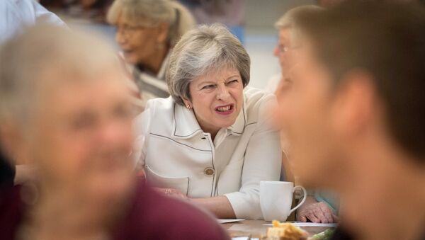 Britain's Prime Minister Theresa May reacts as she talks with people attending a social group in Vauxhall, south London, on October 15, 2018, where she launched the government's loneliness strategy - Sputnik International