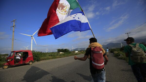 A migrant carrying the flags of Mexico and Honduras gives a thumbs-up to a moto rickshaw driver who stopped to take their picture, as a thousands-strong caravan of Central Americans hoping to reach the U.S. border moves onward from Juchitan, Oaxaca state, Mexico, Thursday, Nov. 1, 2018. Thousands of migrants resumed their slow trek through southern Mexico on Thursday, after attempts to obtain bus transport to Mexico City failed - Sputnik International