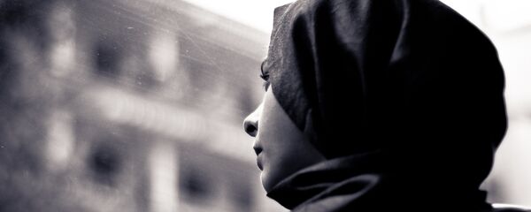 A woman wearing a hijab looks through the window - Sputnik International