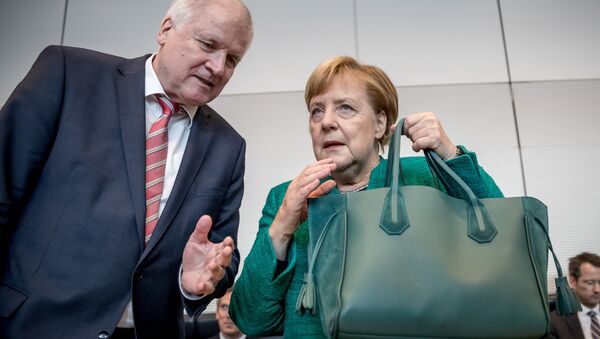 German Chancellor and leader of the Christian Democratic Union (CDU) Angela Merkel holds her hand bag as she confers with German Interior Minister Horst Seehofer at the beginning of a session on September 25, 2018 in the parliamentary compound of the Bundestag, where the parliamentary group is to elect their president - Sputnik International