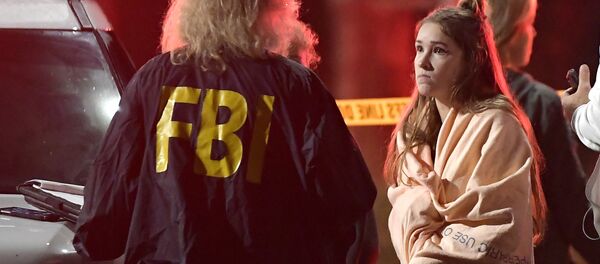 An FBI agent talks to a potential witness as they stand near the scene Thursday, Nov. 8, 2018, in Thousand Oaks, Calif. where a gunman opened fire Wednesday inside a country dance bar crowded with hundreds of people on college night, wounding 11 people including a deputy who rushed to the scene - Sputnik International