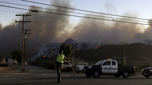 A police officer mans a checkpoint in front of an advancing wildfire Thursday, Nov. 8, 2018, near Newbury Park, Calif. The Ventura County Fire Department has also ordered evacuation of some communities in the path of the fire, which erupted a few miles from the site of Wednesday night's deadly mass shooting at a Thousand Oaks bar. - Sputnik International