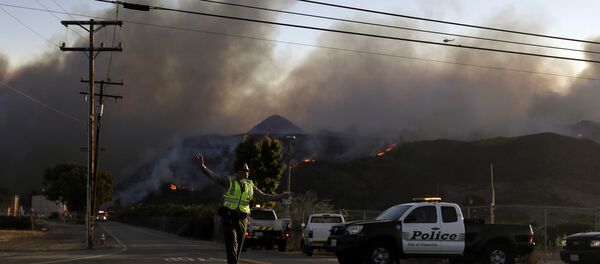 A police officer mans a checkpoint in front of an advancing wildfire Thursday, Nov. 8, 2018, near Newbury Park, Calif. The Ventura County Fire Department has also ordered evacuation of some communities in the path of the fire, which erupted a few miles from the site of Wednesday night's deadly mass shooting at a Thousand Oaks bar. A police officer mans a checkpoint in front of an advancing wildfire Thursday, Nov. 8, 2018, near Newbury Park, Calif. The Ventura County Fire Department has also ordered evacuation of some communities in the path of the fire, which erupted a few miles from the site of Wednesday night's deadly mass shooting at a Thousand Oaks bar. - Sputnik International