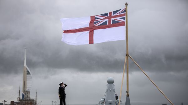 A naval officer looks up at the white ensign flying at the stern of the aircraft carrier HMS Queen Elizabeth, which has been beset with technical problems - Sputnik International
