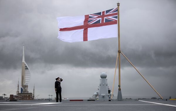 A naval officer looks up at the white ensign flying at the stern of the aircraft carrier HMS Queen Elizabeth, which has been beset with technical problems  - Sputnik International