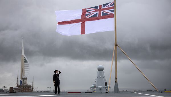 A naval officer looks up at the white ensign flying at the stern of the aircraft carrier HMS Queen Elizabeth, which has been beset with technical problems - Sputnik International