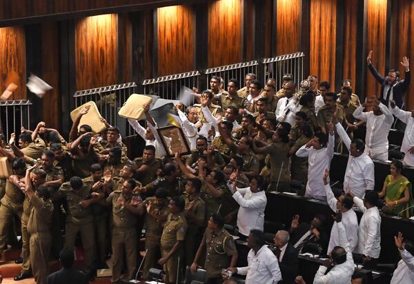 Sri Lankan police escort parliament speaker Karu Jayasuriya (C holding microphone) as aides hold up cushions to protect him and themselves from projectiles thrown by rival legislators in the assembly hall in Colombo on November 16, 2018 Sri Lankan police escort parliament speaker Karu Jayasuriya (C holding microphone) as aides hold up cushions to protect him and themselves from projectiles thrown by rival legislators in the assembly hall in Colombo on November 16, 2018 - Sputnik International