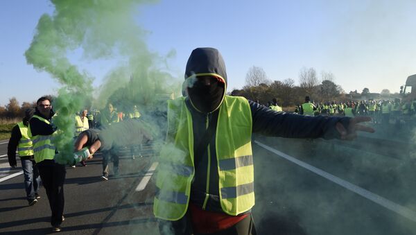 A man holds a flare as demonstrators wearing yellow vests (Gilets jaunes) protest against the rising of the fuel and oil prices on November 17, 2018 in Haulchien near Valenciennes, northern France. - Sputnik International