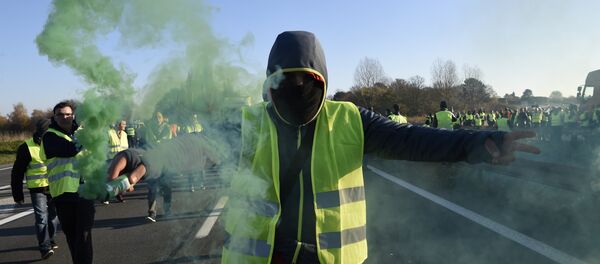 A man holds a flare as demonstrators wearing yellow vests (Gilets jaunes) protest against the rising of the fuel and oil prices on November 17, 2018 in Haulchien near Valenciennes, northern France. A man holds a flare as demonstrators wearing yellow vests (Gilets jaunes) protest against the rising of the fuel and oil prices on November 17, 2018 in Haulchien near Valenciennes, northern France. - Sputnik International