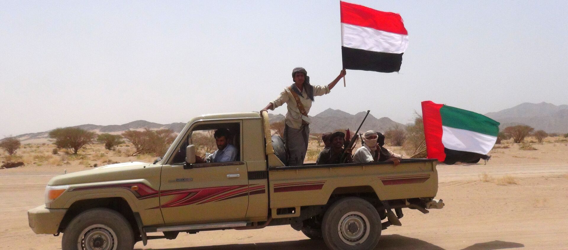 Yemeni tribesmen from the Popular Resistance Committees, supporting forces loyal to Yemen's Saudi-backed fugitive President Abedrabbo Mansour Hadi, hold the Emirati (R) and Yemeni flag as they drive in Marib province, east of the Yemeni capital, Sanaa, on September 20, 2015 - Sputnik International, 1920, 10.03.2021