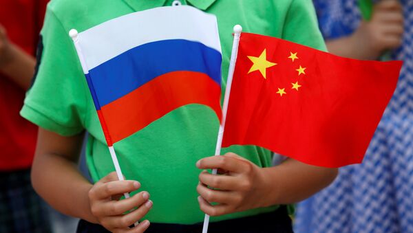 A child holds the national flags of Russia and China prior to a welcoming ceremony for Russian President Vladimir Putin outside the Great Hall of the People in Beijing, China, June 25, 2016 - Sputnik International
