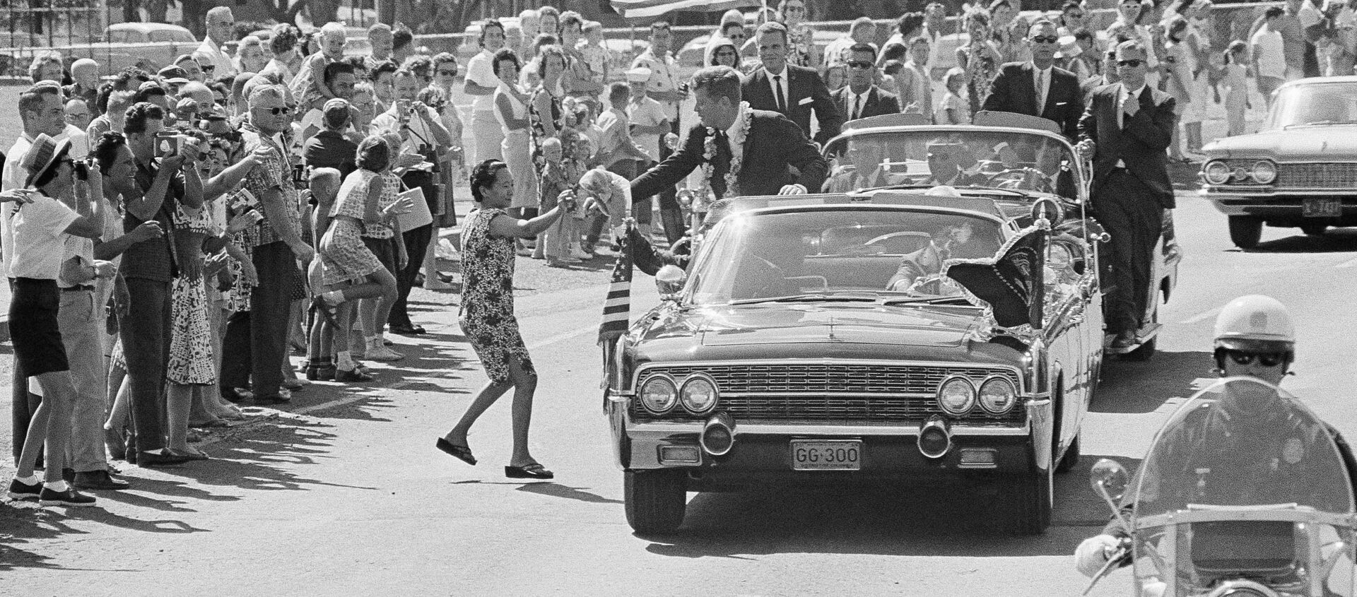 A woman runs into the street and tosses President John Kennedy a floral lei, which he caught,during a motorcade through Honolulu June 9, 1963 from the Pearl Harbor Naval Base to a Waikiki Beach Hotel where he made a strong plea for civil rights before a conference of the nation's mayors - Sputnik International, 1920, 22.11.2018