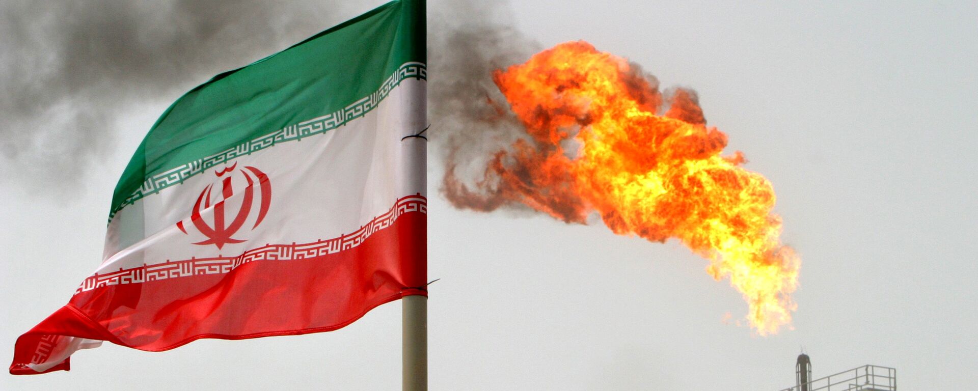 A gas flare on an oil production platform in the Soroush oil fields seen alongside an Iranian flag - Sputnik International, 1920, 25.10.2021
