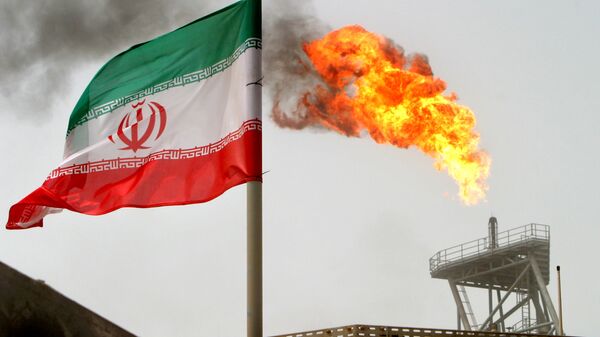 A gas flare on an oil production platform in the Soroush oil fields seen alongside an Iranian flag - Sputnik International
