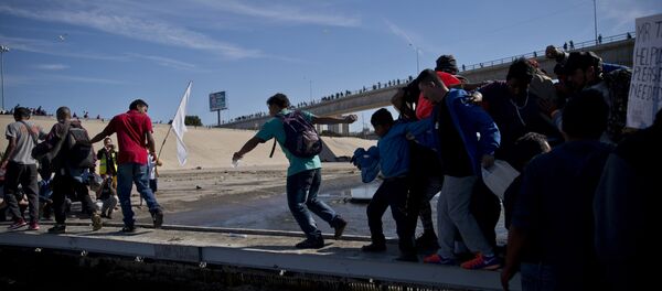 Migrants cross the river at the Mexico-U.S. border after getting past a line of Mexican police at the Chaparral crossing in Tijuana, Mexico, Sunday, Nov. 25, 2018 Migrants cross the river at the Mexico-U.S. border after getting past a line of Mexican police at the Chaparral crossing in Tijuana, Mexico, Sunday, Nov. 25, 2018 - Sputnik International