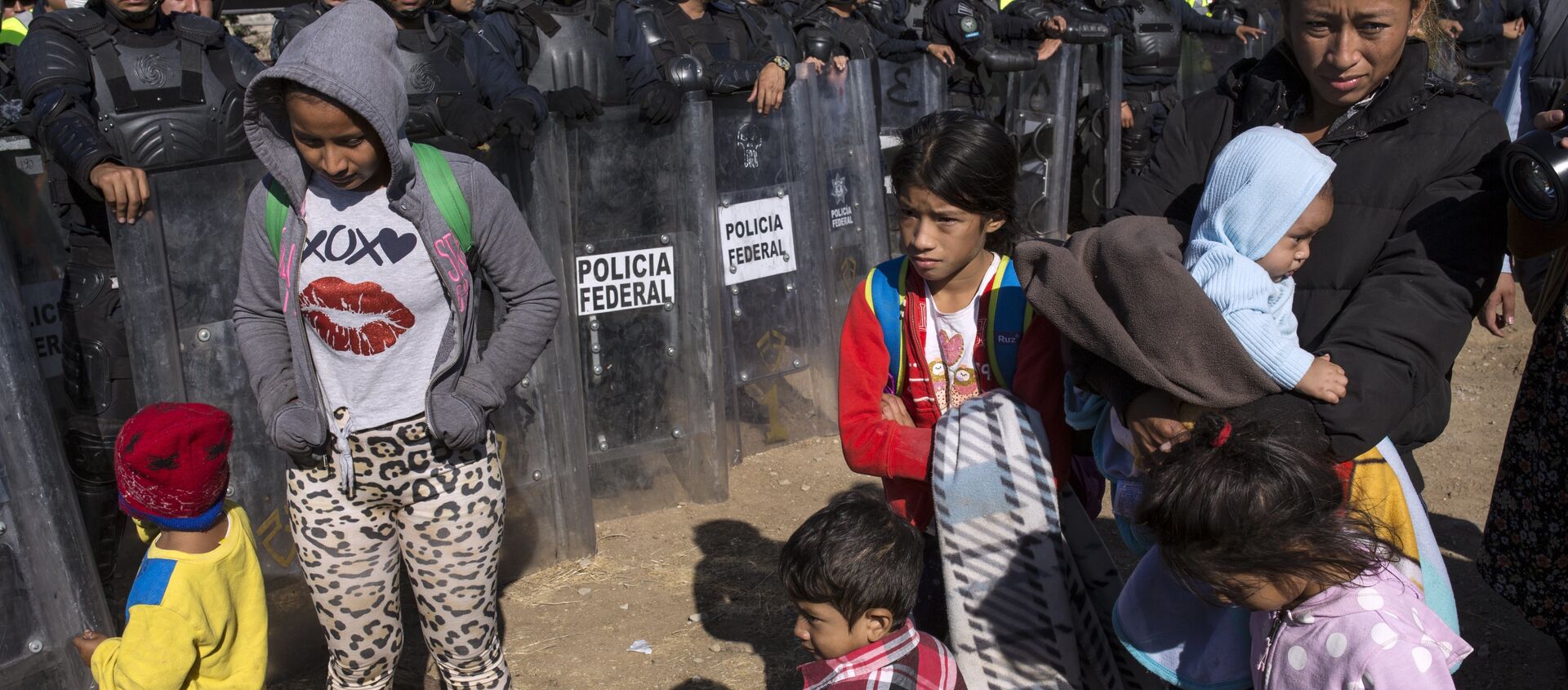 Migrants stand near Mexican police at the Mexico-U.S. border in Tijuana, Mexico, Sunday, Nov. 25, 2018, as they try to reach the US. - Sputnik International, 1920, 11.08.2021