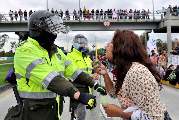 A student blows soap bubbles at a policeman during a school funding march in Colombia - Sputnik International