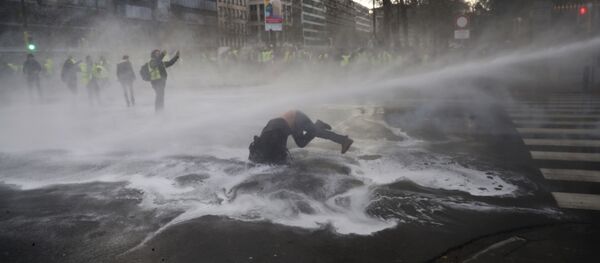 A demonstrator gets hit by a water cannon during a protest of the yellow jackets in Brussels, Friday, Nov. 30, 2018 - Sputnik International