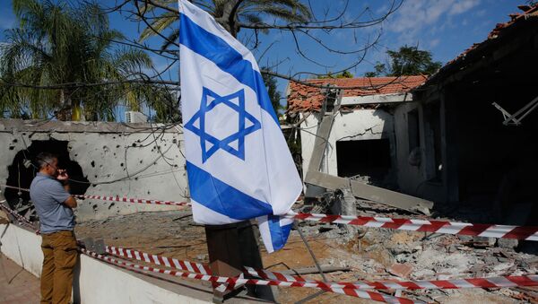 Israelis raise their national flag as they inspect the damage in a house caused by rockets fired from the Gaza Strip, in the southern Israeli town of Ashkelon, on November 13, 2018 - Sputnik International