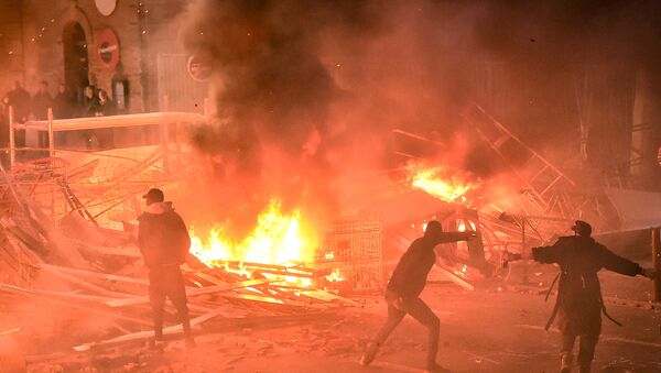 Protestors throw projectiles in a burning barricade during a demonstration of yellow vests (gilets jaunes) against rising costs of living they blame on high taxes in Toulouse, southern France, on December 8, 2018 - Sputnik International