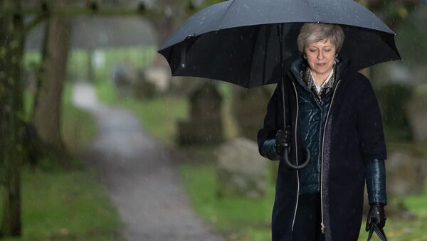 Britain's Prime Minister Theresa May shelters from the rain under an umbrella after attending a church service near to her Maidenhead constituency, west of London on December 9, 2018 - Sputnik International