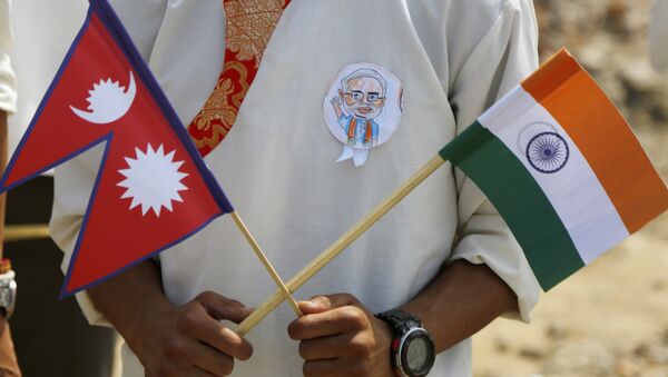 A school student holds a Nepalese and Indian flag and wears a badge with a portrait of Indian Prime Minister Narendra Modi as he waits to welcome Modi in Kathmandu, Nepal, Friday, May 11, 2018 - Sputnik International