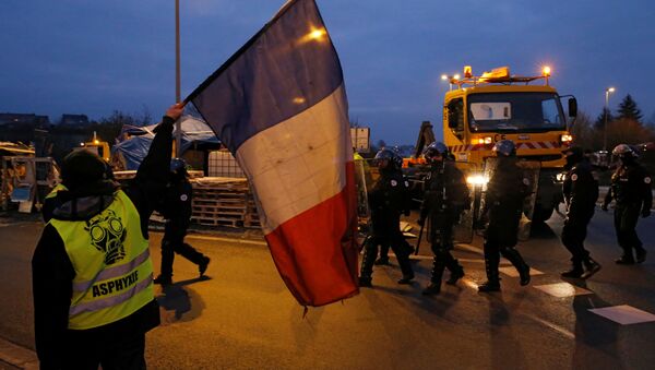 A protester wearing a yellow vests holds a French flag as police arrive to secure the site as their shelter at a traffic island is dismantled near the A2 Paris-Brussels motorway in Fontaine-Notre-Dame, France, December 14, 2018 - Sputnik International