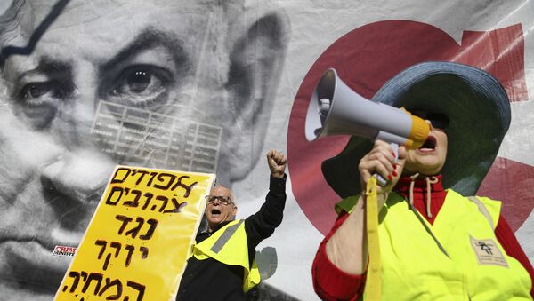 Israelis chant slogans next to a banner showing Israeli Prime Minister Benjamin Netanyahu during a protest against the rising cost of living, in Tel Aviv, Israel, Friday, Dec. 14, 2018. Sign in Hebrew reads Yellow vests against the rising cost of living. - Sputnik International