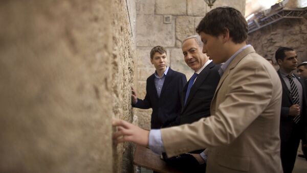 In this Jan. 22, 2013 file photo, Israeli Prime Minister Benjamin Netanyahu, center, prays with his sons Yair, background, and Avner, right, at the Western Wall, the holiest site where Jews can pray, in Jerusalem's Old City. Israeli political leaders are lashing out at Prime Minister Benjamin Netanyahu's eldest son for posting an anti-Semitic caricature aimed at his father's critics - Sputnik International