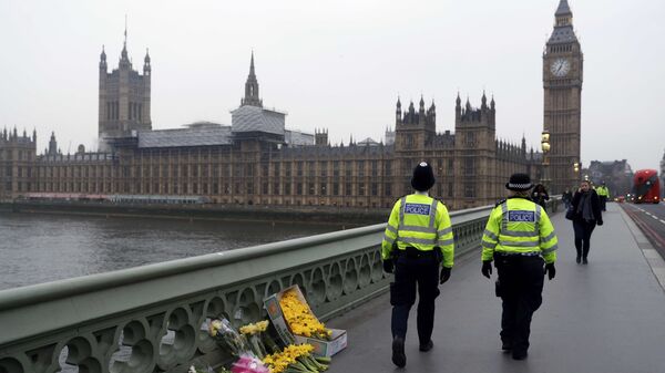 Police officers walk past floral tributes placed at the scene of an attack on Westminster Bridge, in London, Britain March 24, 2017 - Sputnik International