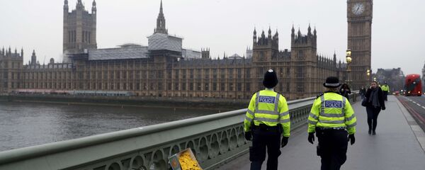 Police officers walk past floral tributes placed at the scene of an attack on Westminster Bridge, in London, Britain March 24, 2017 - Sputnik International
