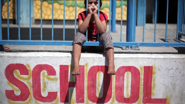 In this Monday, July 14, 2014 photo, a Palestinian girl sits on the wall of the New Gaza United Nations School, where dozens of families have sought refuge after fleeing their home in fear of Israeli airstrikes - Sputnik International
