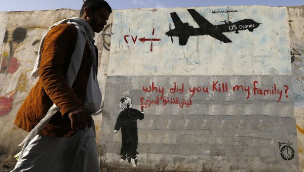 A man walks past a graffiti, denouncing strikes by U.S. drones in Yemen, painted on a wall in Sanaa, Yemen - Sputnik International